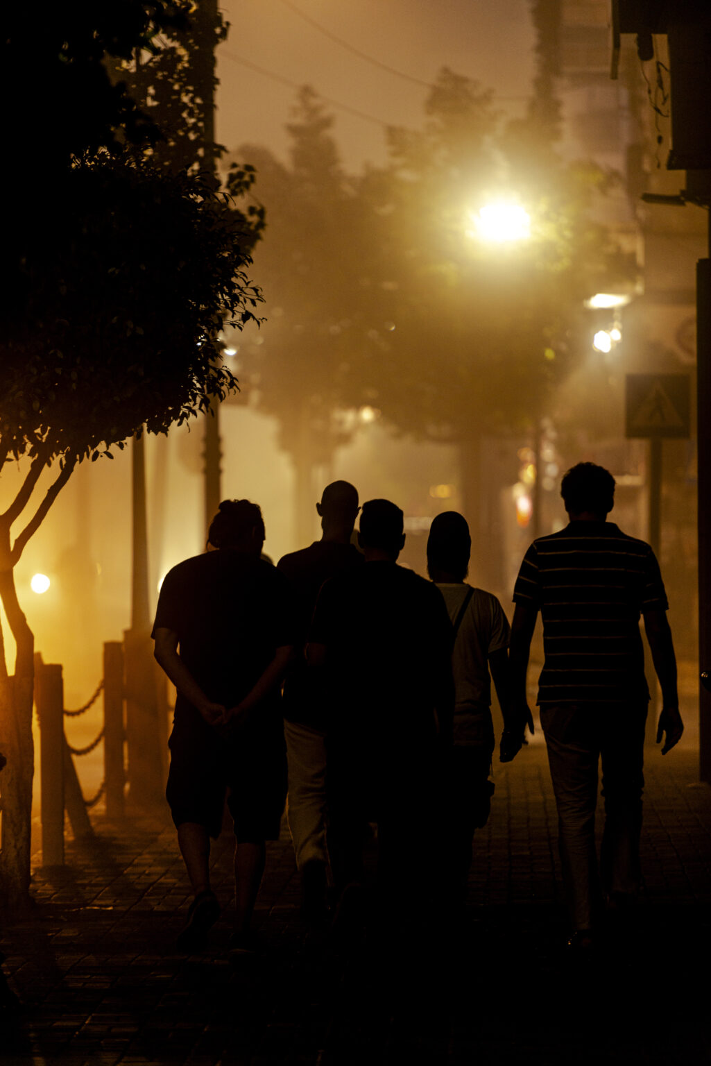 Ramallah, Palestine - backlit photo of a group of young tourists walking through the streets of Ramallah at night