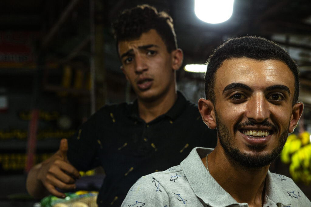 Ramallah, Palestine - Marketplace - young vendors pose amused by the idea of being caught by my camera. Some vegetable stalls can be recognized in the background
