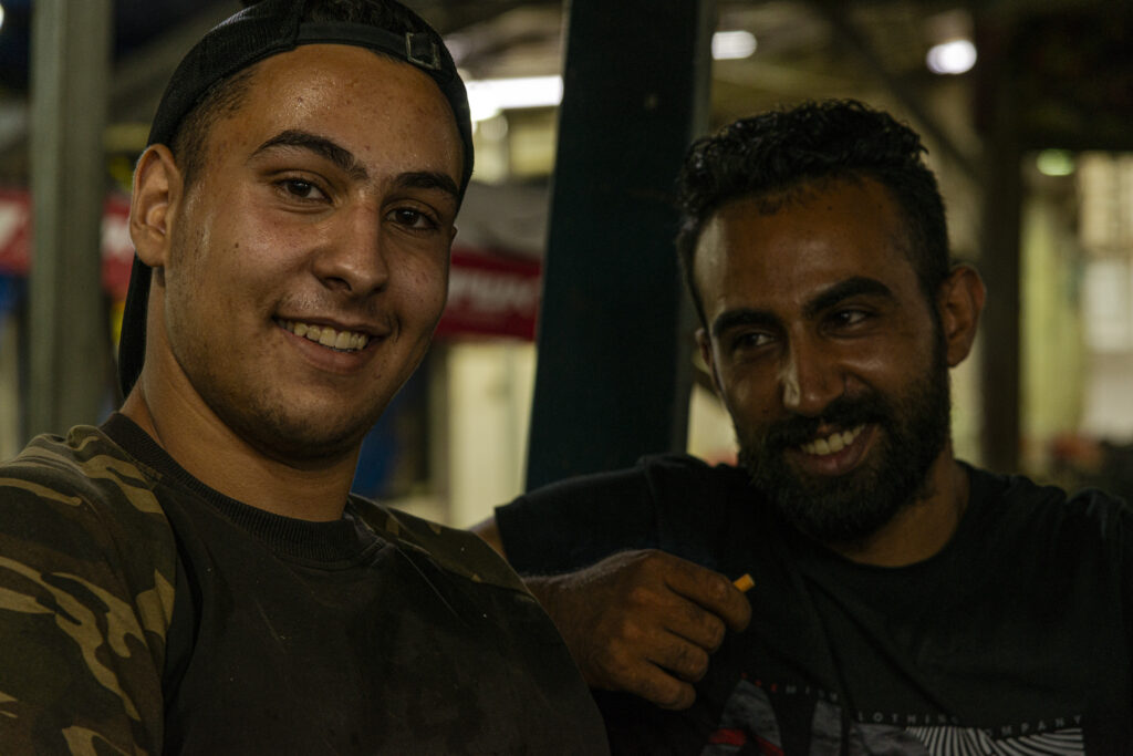 Ramallah, Palestine - Marketplace - two young workers on a forklift smile on camera