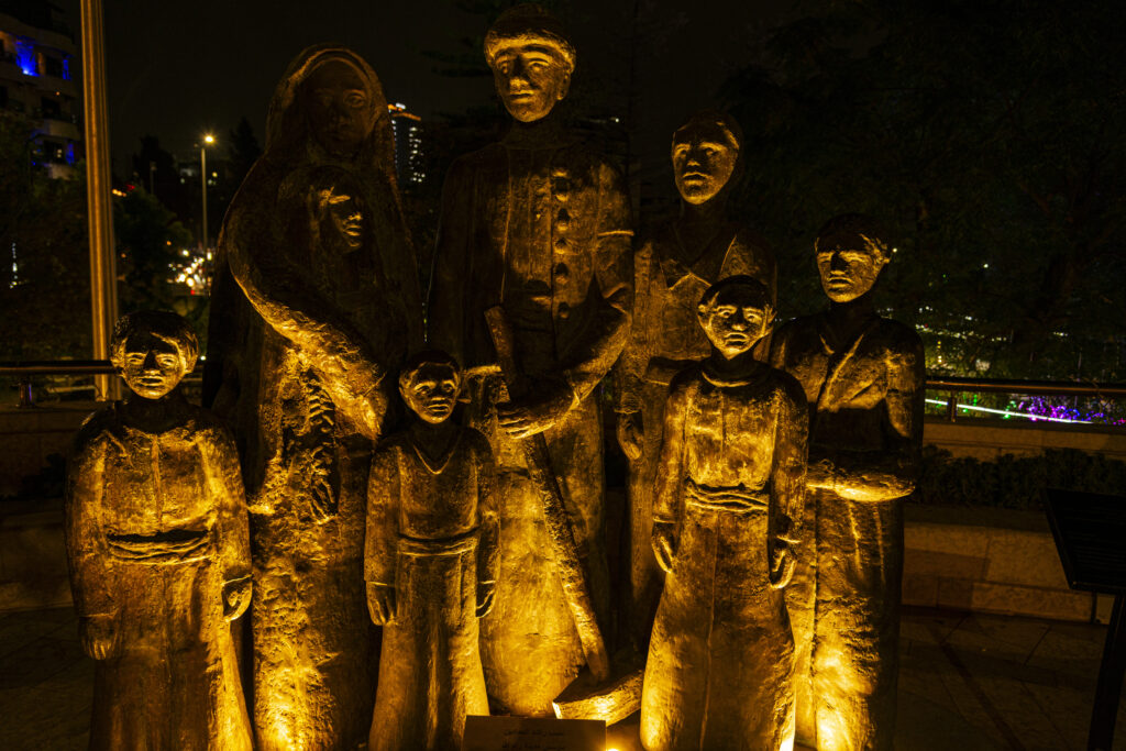 Ramallah, Palestine - Statues of Rashid Haddadin the founder of Ramallah, created by artists Nabil Anani and Sliman Mansour, photographed at night. A light illuminates them from below.