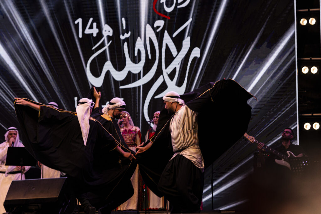 Ramallah, Palestine - A group of young dancers perform on a stage where traditional Palestinian folk music is played. The dancers wear traditional counter and black clothes and on their heads they wear a traditional Keffiyeh of Palestine in black and white. During the dance