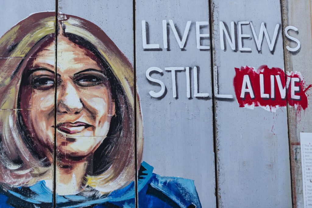 Bethlehem, a graffiti on the separation wall shows Shireen Abu Akleh, the Al Jazeera journalist killed in May 2022 by an Israeli sniper. The journalist is depicted with the bulletproof vest that war journalists wear. A writing says "Live news still alive".