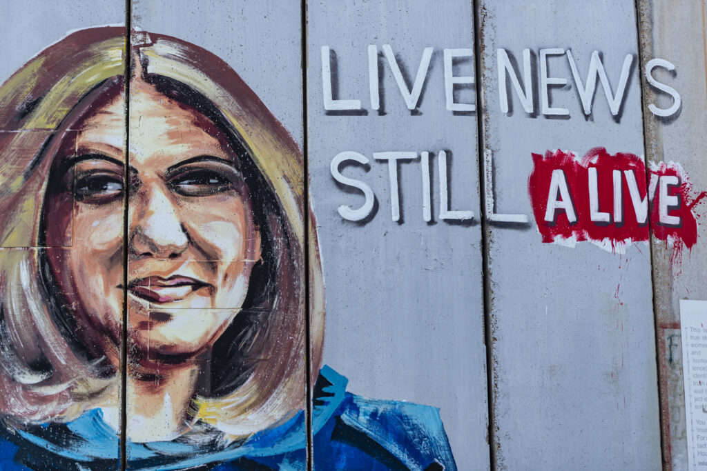 Betlemme, un graffito sul muro di separazione mostra Shireen Abu Akleh, la giornalista di Al Jazeera uccisa nel maggio 2022 da un cecchino israeliano. La giornalista è rappresentata con il giubbotto antiproiettili che indossano i giornalisti di guerra. Una scritta dice "Live news still alive".