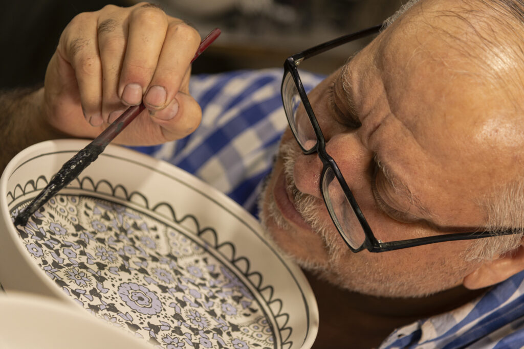 An artisan is intent on decorating a ceramic bowl in one of Herbon's many workshops