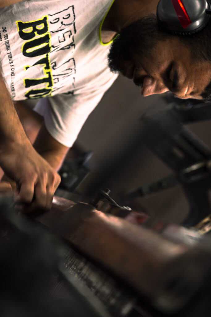 Palestine's last Kufiyah factory in Hebron. A young craftsman is pictured a close-up working at the loom on a purple Kufiyah. He wears headphones to protect his ears from the noise of the incessantly working machines.