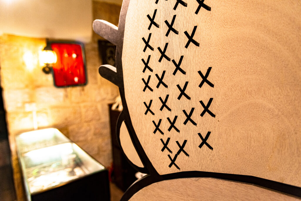 The entrance to Handala Café. In the photo, taken with a wide angle lens, you can see in the foreground a detail of the design of Handala's head, carved into a wooden panel, and the entrance counter in the background.