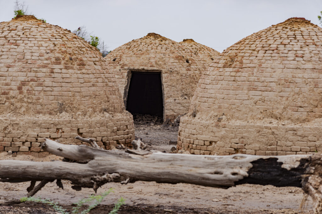 Hemispherical brick constructions are used for coal production. These are furnaces in which wood, due to the low amount of oxygen, is allowed to burn for several hours. Incomplete combustion turns the wood into charcoal that is normally used in houses. Three of these furnaces can be seen in the photo.