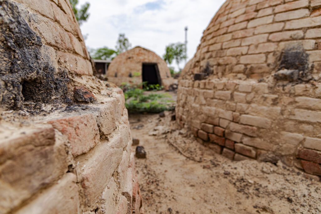 Hemispherical brick constructions are used for coal production. These are furnaces in which wood, due to the low amount of oxygen, is allowed to burn for several hours. Incomplete combustion turns the wood into charcoal that is normally used in houses. The photo shows one kiln in the background and the circular walls of two other kilns. Of one of the two ovens you can see a hole that is used to ignite the flame and feed the fire with oxygen from outside.