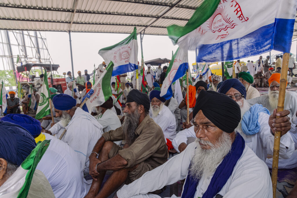 A group of men sit under the tensile structure that has been erected along the highway leading from Punjab to Delhi, at the Shambhu Border.