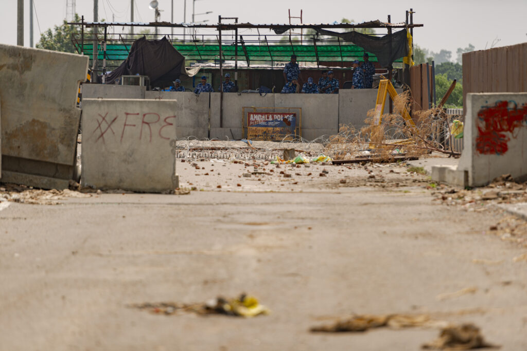 The police blockade at the Shambhu Border between Punjab and Haryana. Concrete jerseys, nails on the road, and a police outpost with several policemen deployed can be seen on the road.